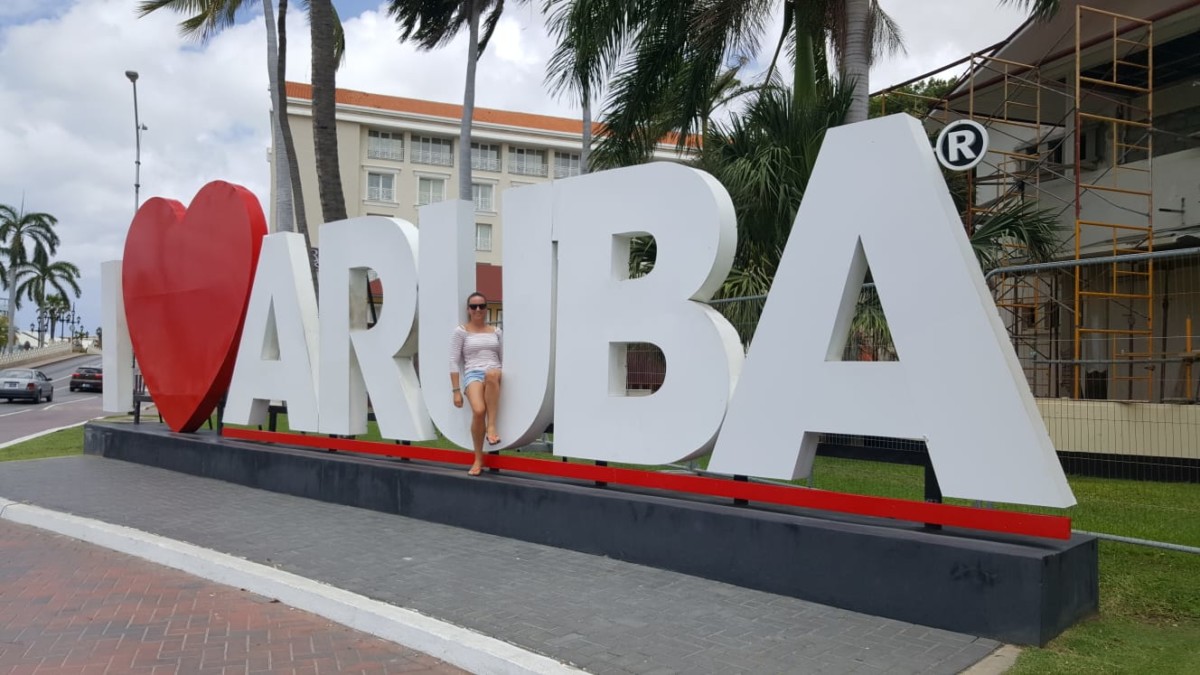 Frau sitzt auf einem Schriftzug Love Aruba